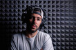 © Jose Carlos Gutierrez/ADDICTIVE STOCK - Stylish male singer wearing headphones standing in recording studio on background of soundproof acoustic panel and looking at camera