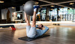 © Jose Carlos Cerdeno/ADDICTIVE STOCK - Bearded adult male athlete holding legs on fit ball and doing abdominal crunches on mat during fitness training in gym