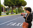 © Jose Carlos Cerdeno/ADDICTIVE STOCK - Full body of confident African American female worker in classy wear waiting for taxi while standing on road using mobile phone
