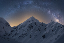 Spectacular View Of High Rough Ridge Covered With Snow Under Colorful Starry Sky During Milky Way Phenomenon