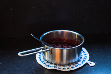 Preparing Cranberry sauce in a metal pan on a dark background