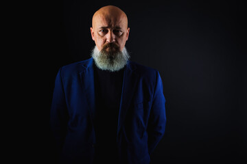 Wall Mural - close up photo, portrait of a serious, thoughtful, bearded man on a dark background confident and dramatic looking straight. Concept of male portrait.  Low key