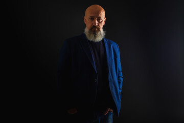 Wall Mural - close up photo, portrait of a serious, thoughtful, bearded man on a dark background confident and dramatic looking straight. Concept of male portrait.  Low key