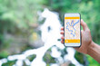 © Pol Sole/ADDICTIVE STOCK - Cropped unrecognizable man traveler using smartphone browsing on map app standing on slope of amazing landscape of green forest with fast river