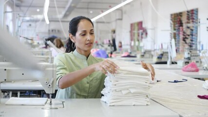 Wall Mural - Dressmaker woman sitting and taking pieces of cloth in factory.