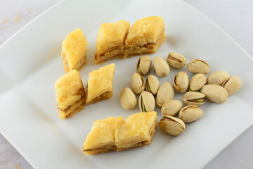 Wall Mural - Pieces of baklava dessert with pistachio nuts on white snack plate