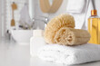 Natural loofah sponges and towel on table in bathroom. Space for text