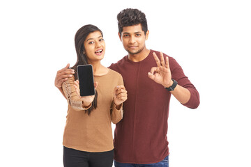 Wall Mural - Beautiful happy young couple holding smart phone on white.