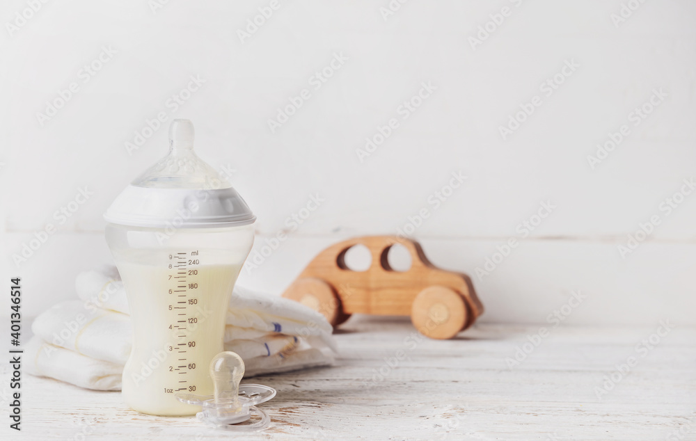 Bottle of milk for baby with accessories on table