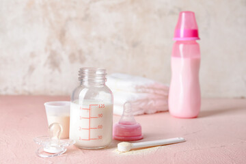 Bottle of baby milk formula and accessories on table