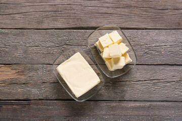 Glass bowls with fresh butter on wooden background