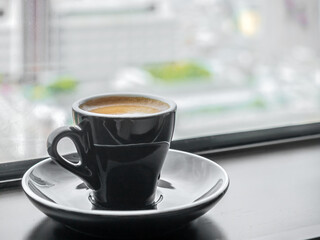 Wall Mural - Coffee in ceramic black cup and round dish beneath at window light view, for background