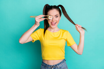 Poster - Photo of young woman dressed yellow t-shirt holding ponytail sushi roll cover eye licking lips showing tongue isolated teal color background