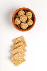 Til chikki and sesame seed ball on white background is an Indian sweet dish made with jaggery and sesame seeds.