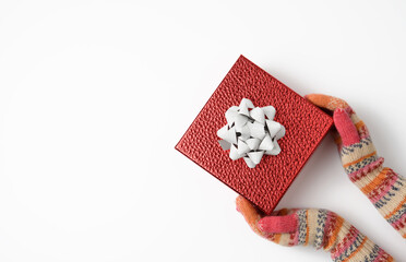 Wall Mural - female hands in knitted mittens hold a red box on a white background