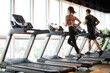 © Blue Jean Images - Young couple running on treadmill at gym