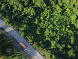 Fototapeta Uliczki - Aerial view of green tropical forest road. Curved road from above