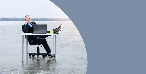 elderly gray-bearded businessman in suit, smiling while talking on smartphone, threw his legs in hockey skates on a table in the middle of a frozen lake in winter. Banner, copy space for text