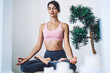 © BullRun - Caucasian fitness girl sitting in apartment for training vitality wellness and tranquility, woman in casual sportive wear recreating on meditation in lotus pose practice yoga for health at home