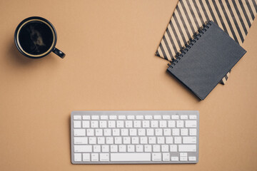 Fototapete - Modern office desk table with computer keyboard, paper notebook, cup of coffee on brown background. Elegant feminine workspace. Flat lay, top view.
