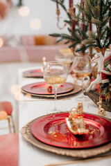  Festive table setting for Christmas. Red and gold shades. Blurred background.Stylish table setting with burning candles and Christmas decorations.