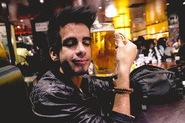 Happy young man hugging with love a big beer jar in a restaurant, Tokyo