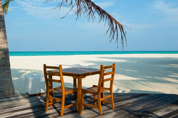 Beautiful table and two chairs on the white sand beach. Restaurant on the shore. Turquoise Ocean landscape