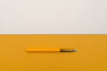 Wall Mural - Stationery paper knife on blank colored paper. Place for text. Top view.