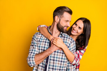 photo portrait of girl hugging boyfriend from behind isolated on vivid yellow colored background