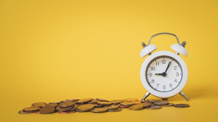 Wall Mural - white analog clock with blurred pile of coins on grunge yellow background for business and finance concept , time for savings money concept, banking and business idea