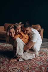 Wall Mural - Photoshoot of a happy young family. Dad, mom and daughter. Studio photography.