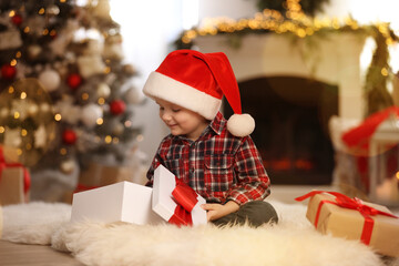 Wall Mural - Cute little boy opening gift box in room decorated for Christmas