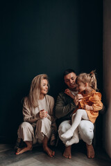 Wall Mural - Photoshoot of a happy young family. Dad, mom and daughter. Studio photography.