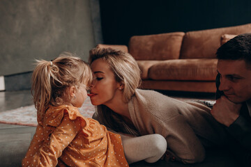 Wall Mural - Photoshoot of a happy young family. Dad, mom and daughter. Studio photography.