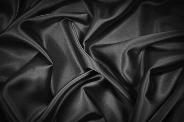 Abstract black background. Black silk satin fabric texture background. Beautiful soft folds on shiny fabric. Black elegant background for your design.
