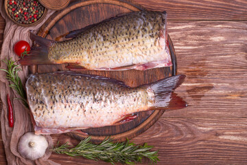 Carcass carp without head and scales, ready to cook on a wooden background. Top view, copy space