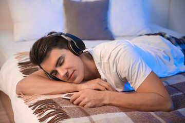 Young man listening to music in bedroom at home