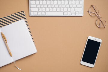 Top view, flat lay keyboard, blank paper notebook, glasses, smartphone on office desk. Feminine workspace. Modern style.