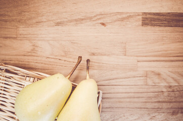 Poster - A top view closeup of two pears on a thatched basket on a wooden table