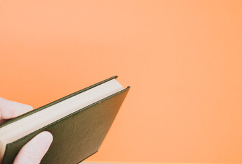 Wall Mural - A top view closeup of an ancient book with a dark green cover isolated on an orange background
