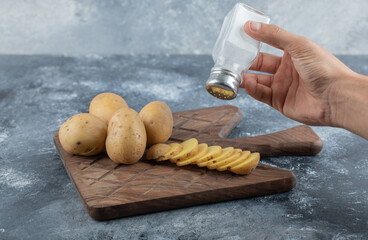 Wall Mural - Man pouring salt over the sliced potatoes