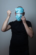 © Vladimir Zlotnik - young man wearing a lot of face protective medical masks for extra protection from virus disease over grey background
