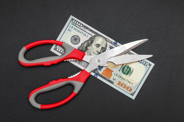 Wall Mural - Scissors with money on black background. Close up. Business concept.