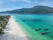 A top view over Koh Lipe island with crystal clear water with many long-tail boats. 
