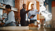 © Gorodenkoff - Multicultural Coffee Shop Owners Meeting Behind the Counter and Working on Tablet Computer and Checking Inventory in a Cozy Loft-Style Cafe. Successful Restaurant Managers and Barista at Work.