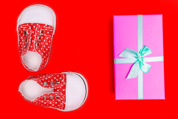 Poster - red baby shoes with white polka dots on a red background with gifts