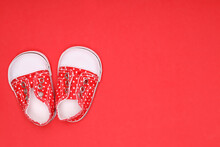 Red Baby Shoes With White Polka Dots On A Red Background