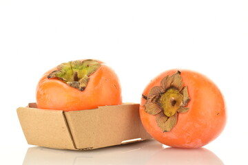 Two sweet juicy persimmons in a paper box, close-up, isolated on white.