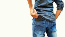 Young Man Pulling Out Wallet From Back Pocket Of Jeans Isolated On White