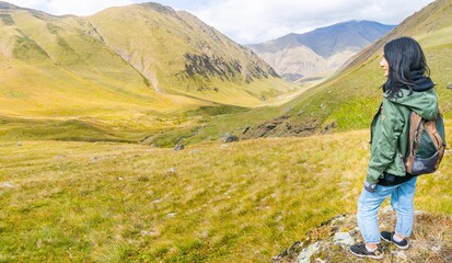 Poster - Panoramic view of woman backpacker smilling and looking left with beautiful view of Juta valley. Inspirational travel solo adventure in KAzbegi